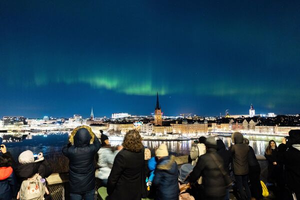 Люди наблюдают за северным сиянием в центре Стокгольма. - Sputnik Латвия