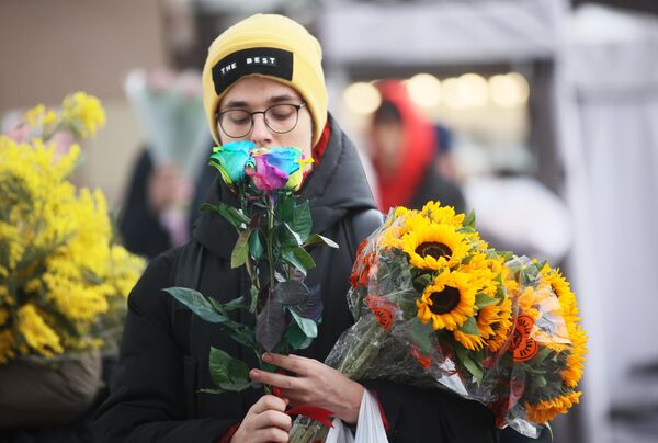 Молодой человек покупает цветы в преддверии Международного женского дня - Sputnik Латвия