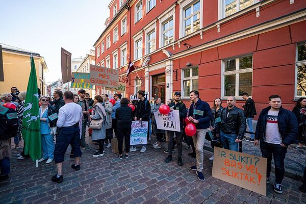 Участники пикета держат плакаты с надписями &quot;С больным народом экономику  не вылечишь&quot;, &quot;Гроб или чемодан&quot;, &quot;Здоровье — это право человека&quot;. - Sputnik Латвия