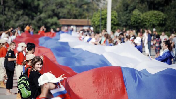Участники праздничных мероприятий в Мариуполе разворачивают 100-метровый флаг России - Sputnik Латвия