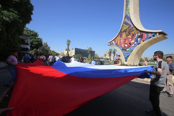 Молодежь поднимает российский флаг на площади Омейядов в Дамаске в рамках празднования Дня флага России, 22 августа 2023 г. - Sputnik Латвия