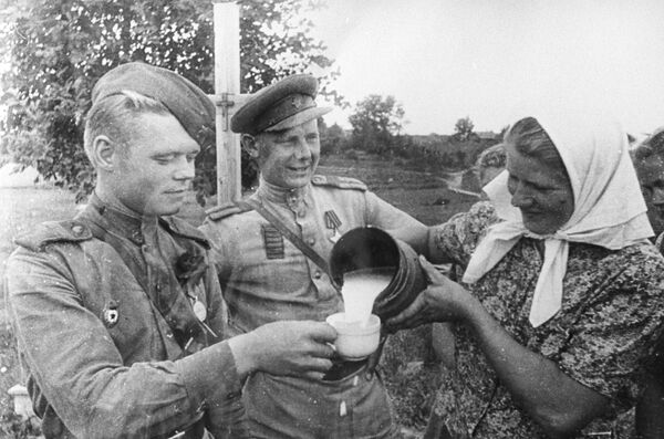 Жительница освобожденной Риги угощает молоком старшего сержанта и старшину Красной армии - Sputnik Латвия