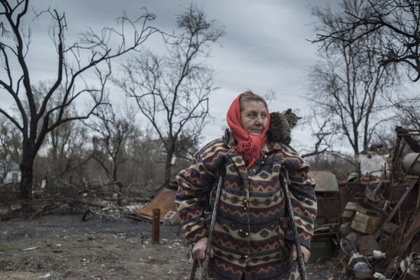 Женщина у разрушенного дома в поселке Саханка Донецкой области - Sputnik Latvija
