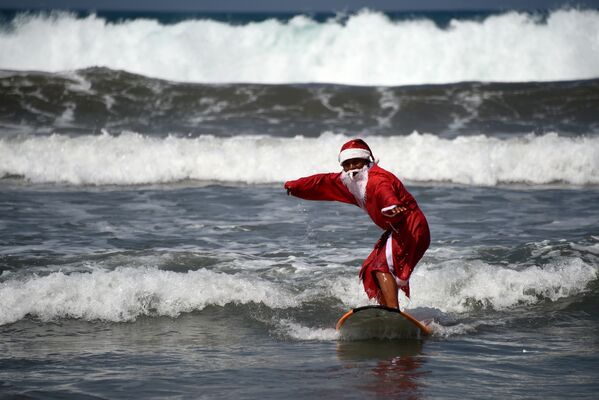 Мужчина в костюме Санта-Клауса во время серфинга на острове Бали  - Sputnik Латвия
