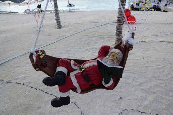 Санта-Клаус во время чтения книги на пляже острова Сен-Мартен - Sputnik Латвия