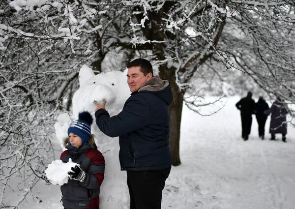 Отец с сыном лепят снеговика на Ангарском перевале в Крыму - Sputnik Латвия