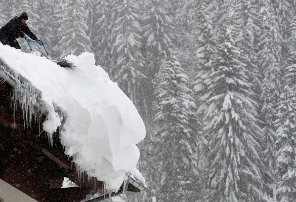 Мужчина убирает снег на крыше во время снегопада в Фильцмос, Австрия - Sputnik Латвия