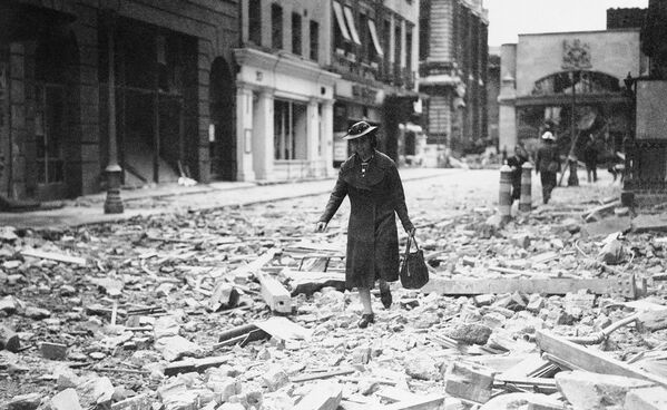 Женщина с сумкой в руках идет по обломкам в Лондоне, 1940 год Женщина с сумкой в руках идет по обломкам в Лондоне, 1940 год - Sputnik Латвия