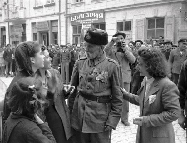 Ветеран турецкой войны беседует с девушками, в освобожденном войсками РККА от фашистов, болгарском городе, 1944 год Ветеран турецкой войны беседует с девушками, в освобожденном войсками РККА от фашистов, болгарском городе, 1944 год - Sputnik Латвия