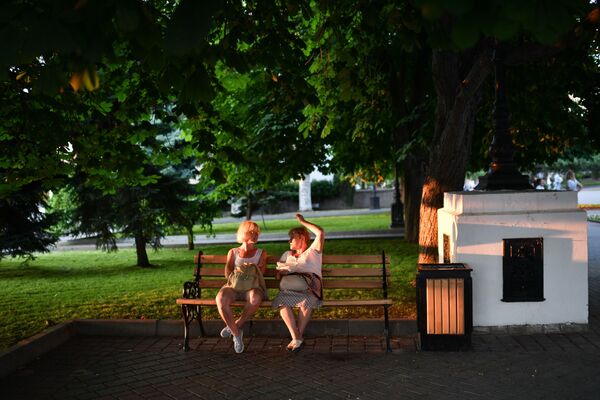 Отдыхающие сидят на скамейке в парке в Севастополе в Крыму Отдыхающие сидят на скамейке в парке в Севастополе в Крыму - Sputnik Латвия