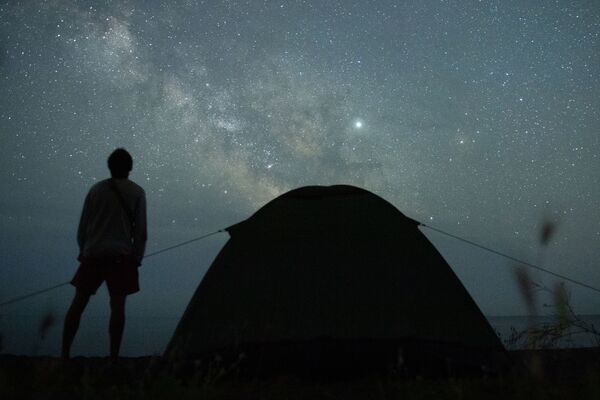 Мужчина наблюдает за звездным небом на берегу Черного моря возле поселка Морское в Крыму - Sputnik Латвия