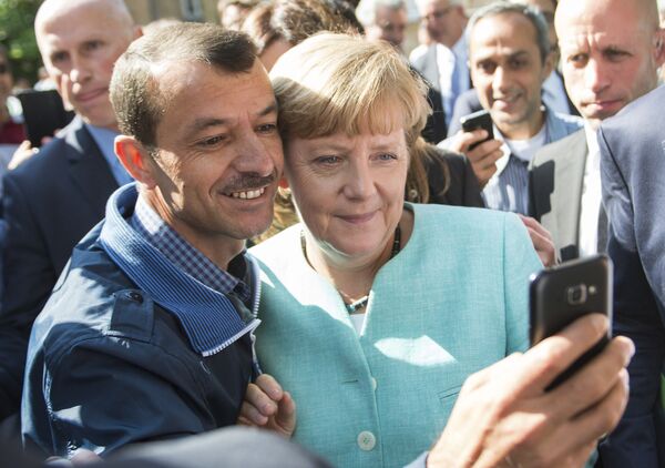Беженец делает селфи с канцлером Германии Ангелой Меркель во время ее визита в центр для новоприбывших беженцев в Берлине - Sputnik Латвия