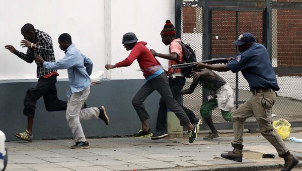 Полицейский разгоняет демонстрантов на антимигрантском митинге в Претории, ЮАР. - Sputnik Латвия