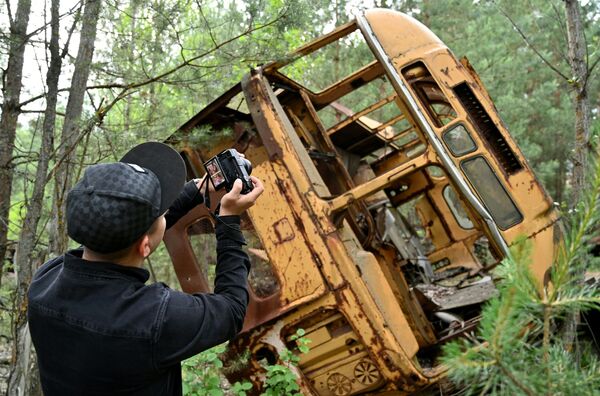 Турист фотографирует автобус в зоне отчуждения Чернобыльской АЭС - Sputnik Латвия