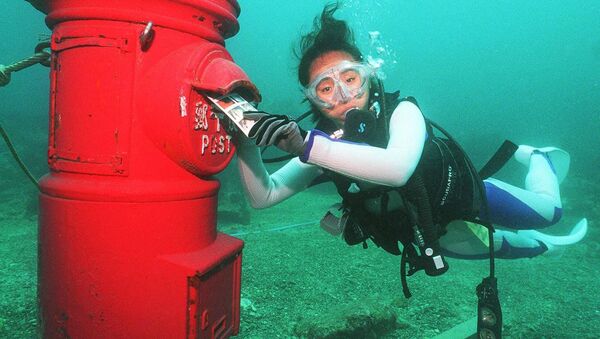 Водолаз кладет пластиковое письмо в почтовый ящик, установленный на глубине 10 метров на дне моря у берегов Сузами в префектуре Вакаяма - Sputnik Латвия