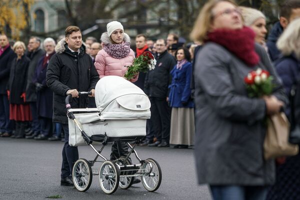 Семья с ребенком идет к памятнику Свободы, чтобы возложить цветы Семья с ребенком идет к памятнику Свободы, чтобы возложить цветы - Sputnik Латвия