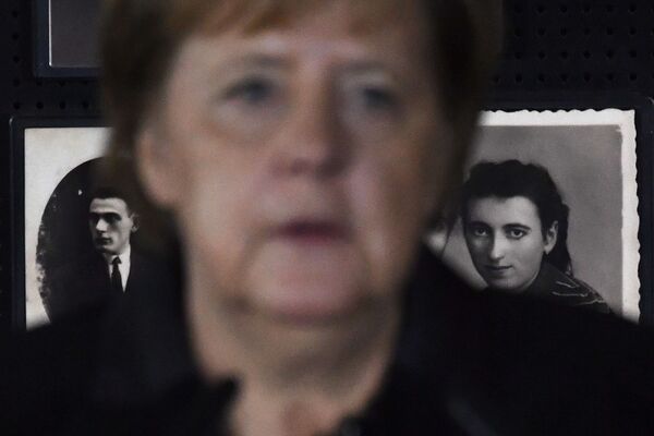 Канцлер Германии Ангела Меркель на фоне фотографий жертв Холокоста в музее Аушвиц-Биркенау в Освенциме. - Sputnik Латвия