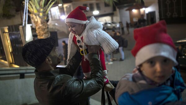Мужчина играет с ребенком до начала рождественской мессы в Газе  - Sputnik Латвия