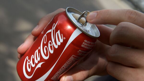 Покупатель держит банку с напитком компании Coca-Cola - Sputnik Латвия