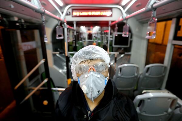 Сотрудник муниципалитета Тегерана дезинфицирует  автобус, чтобы избежать распространения коронавируса - Sputnik Латвия