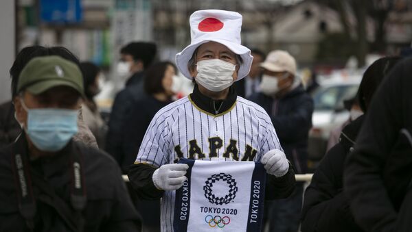 Мужчина держит в руках полотенце с логотипом Олимпийских игр в Токио 2020 - Sputnik Latvija