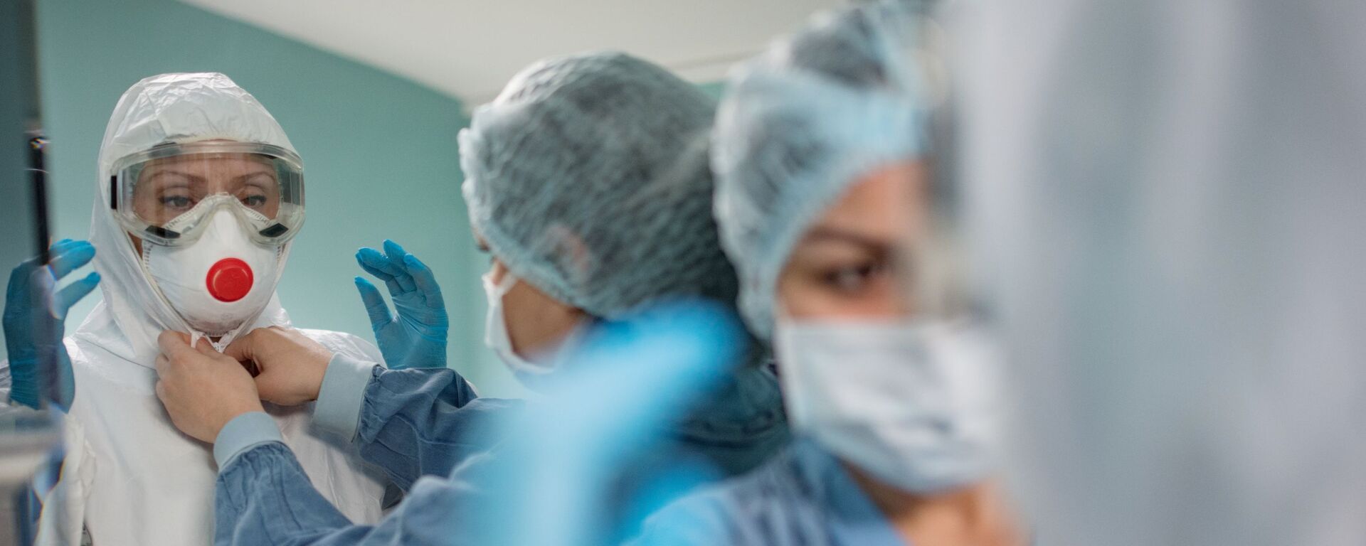 Медицинские работники надевают защитные костюмы и маски для работы с больными с коронавирусной инфекцией - Sputnik Латвия, 1920, 04.02.2021