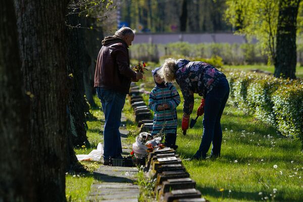 Посетители Братского кладбища ухаживают за могилой своего родственника - Sputnik Латвия