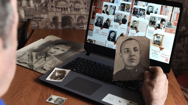 Мужчина смотрит онлайн-трансляцию акции Бессмертный полк - Sputnik Латвия