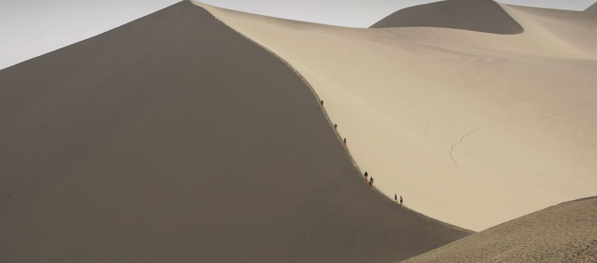 Туристы катаются на верблюдах на краю пустыни, которая угрожает поглотить древний китайский город Дуньхуан  - Sputnik Латвия, 1920, 24.06.2020
