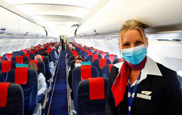 Стюардесса в медицинской маске в салоне самолета в международном аэропорту Брюсселя - Sputnik Латвия