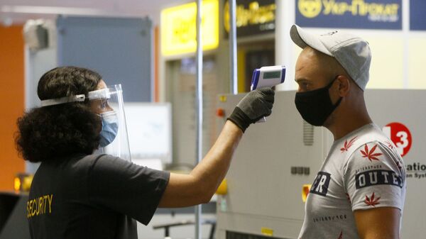 Пассажир в защитной маске проходит температурный контроль в международном аэропорту Борисполь в Киеве - Sputnik Латвия