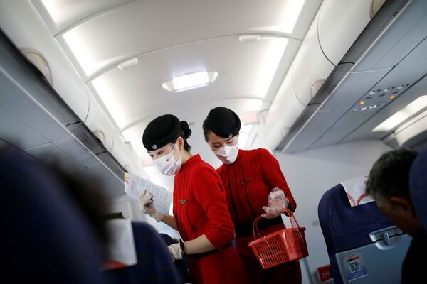 Бортпроводницы в масках и перчатках на борту самолета авиакомпании Сычуань, Китай - Sputnik Латвия