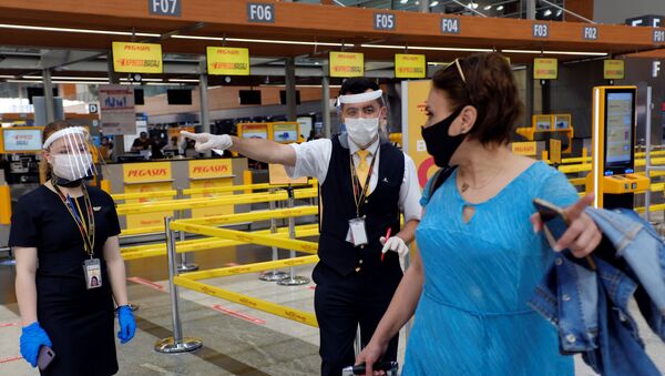 Сотрудники авиакомпании Pegasus Airlines в защитных масках и экранах указывают пассажиру нужное направление в международном аэропорту имени Сабихи Гекчен в Стамбуле - Sputnik Latvija