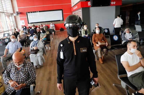 Сотрудник службы безопасности в тепловизионном шлеме следит за пассажирами, ожидающими посадки на рейс в аэропорту Стамбула Сотрудник службы безопасности в тепловизионном шлеме следит за пассажирами, ожидающими посадки на рейс в аэропорту Стамбула - Sputnik Латвия