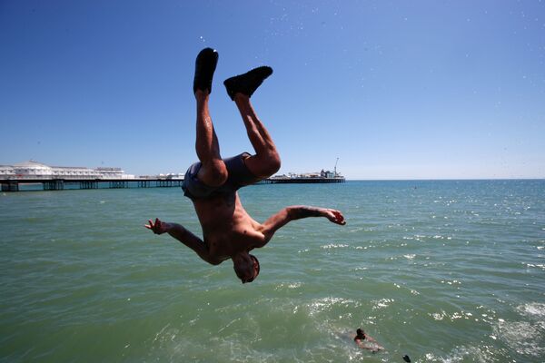 Мужчина прыгает в воду на пляже в Брайтоне, Великобритания - Sputnik Латвия