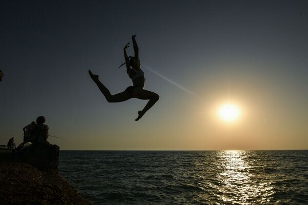 Девушка во время прыжка с пирса на пляже в посёлке городского типа Новофёдоровка Сакского района - Sputnik Латвия