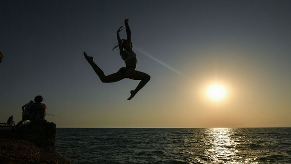 Девушка во время прыжка с пирса на пляже в посёлке городского типа Новофёдоровка Сакского района - Sputnik Latvija