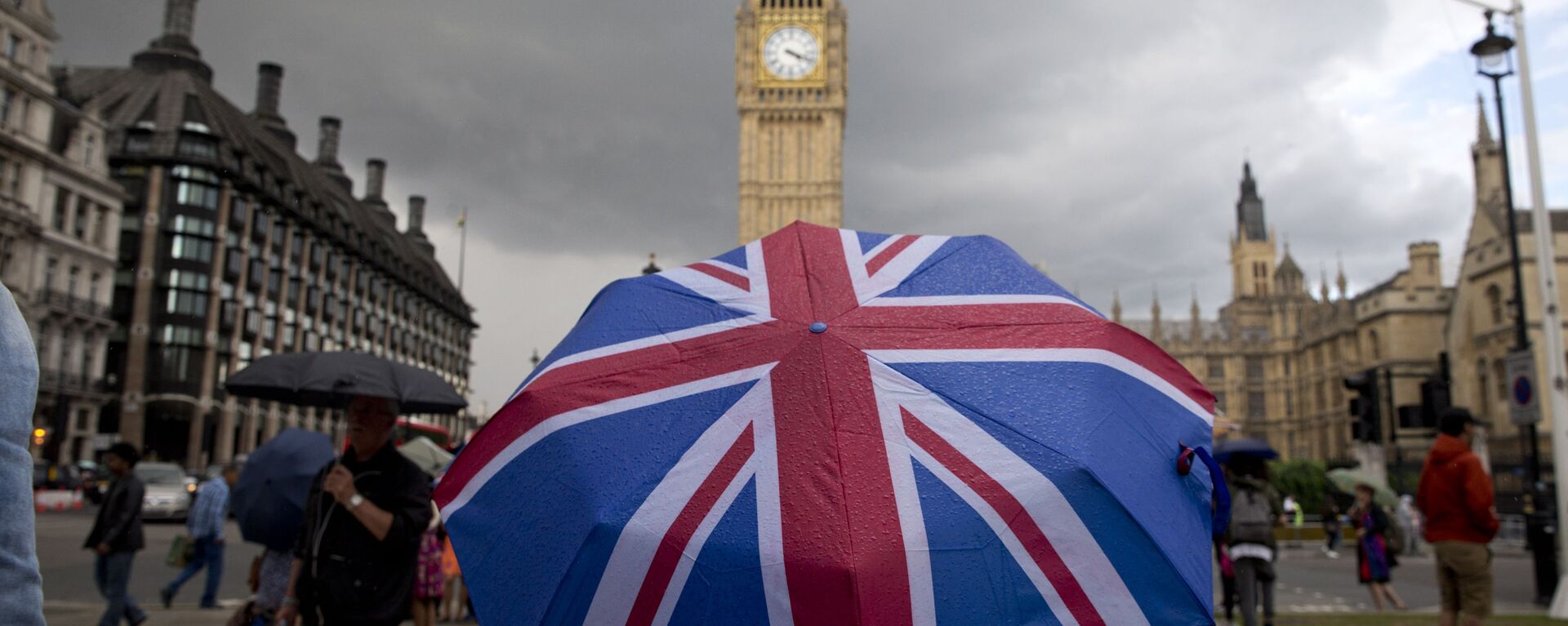 Пешеход с зонтом в цветах британского флага в Лондоне - Sputnik Латвия, 1920, 26.09.2021