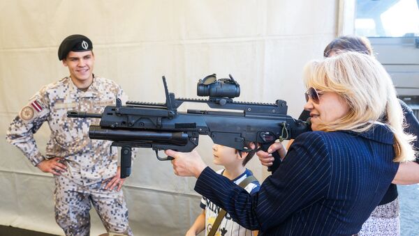 Rīgas iedzīvotāja ar Latvijas Bruņoto spēku standarta šauteni Heckler-Koch G36 - Sputnik Latvija
