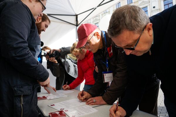 Сбор подписей под обращением к депутатам 12 Сейма. Подписывает руководитель профсоюза медиков Валдис Керис (в кепке) Сбор подписей под обращением к депутатам 12 Сейма. Подписывает руководитель профсоюза медиков Валдис Керис (в кепке) - Sputnik Латвия