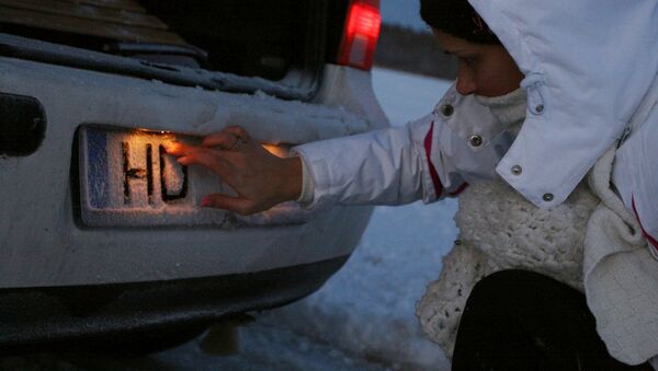 Девушка чистит номер автомашины от снега - Sputnik Латвия