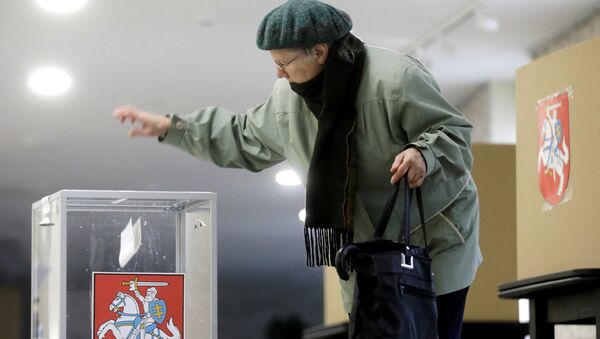 Женщина опускает бюллетень в урну для голосования в Биржае, Литва - Sputnik Латвия