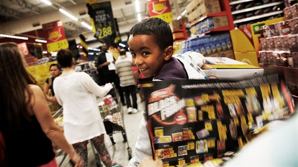 Ребенок едет в корзине с покупками на Черной пятнице в магазине в Сан-Паулу - Sputnik Латвия