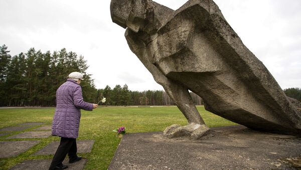 Sieviete noliek ziedus pie figūras Nesalauztais Salaspils Memoriālajā kompleksā - Sputnik Latvija