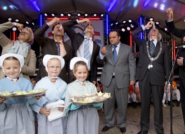 Голландский министр финансов Ян Кеес де Ягер и мэр Гааги Йозиас Ван Аартсен кушают селедку во время праздника День селедки в Схевенингене - Sputnik Латвия