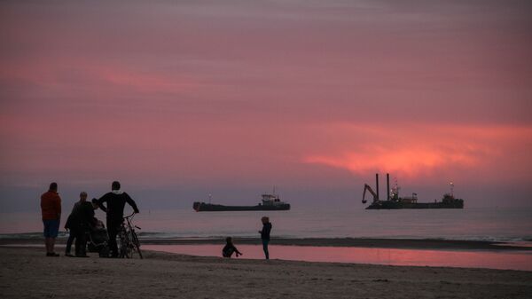 Закат на пляже в Павилосте, на фоне - рыбацкие суда и отдыхающие - Sputnik Латвия