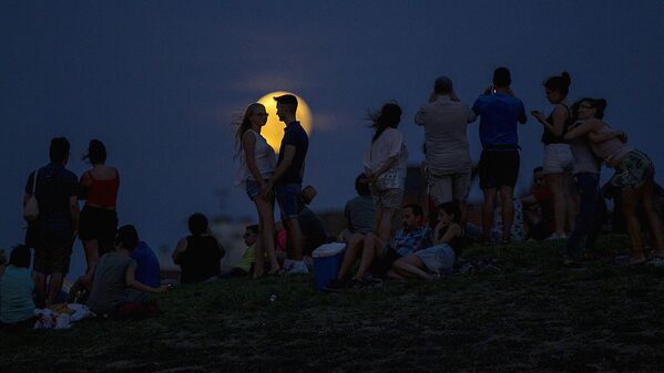 Люди наблюдают за восходящей луной во время частичного лунного затмения на вершине холма в парке Тио Пио в Мадриде - Sputnik Латвия