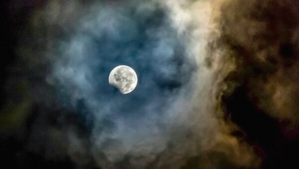 Луна, обрамленная пеплом от вулкана Маунт Синабунг, видна во время частичного лунного затмения в провинции Северная Суматра в Индонезии - Sputnik Latvija