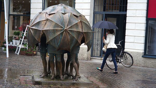Люди под зонтом во время дождя, памятник непогоде - Sputnik Latvija