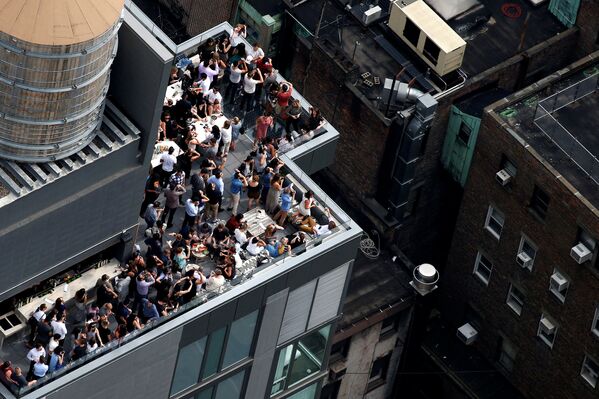 Люди наблюдают за солнечным затмением из бара на крыше в центре Манхэттена в Нью-Йорке - Sputnik Латвия